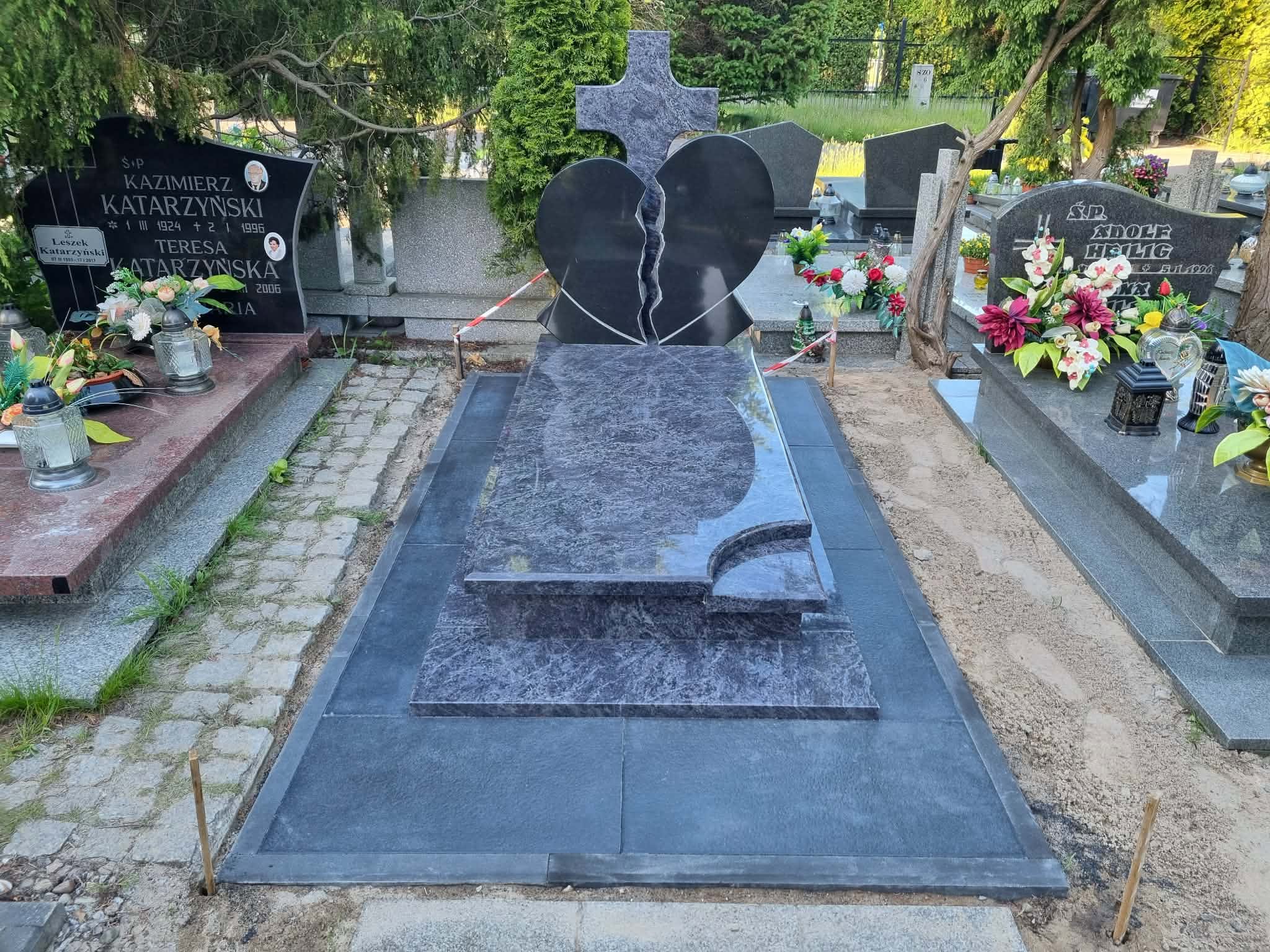 Nagrobek w kształcie pękniętego serca z krzyżem z szarego granitu